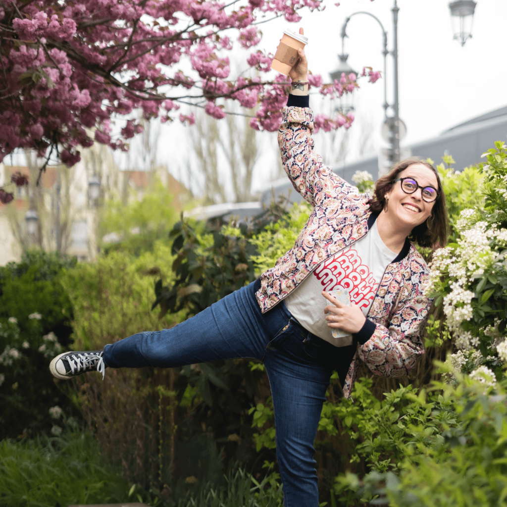 Angélique debout devant arbre en fleur avec du café